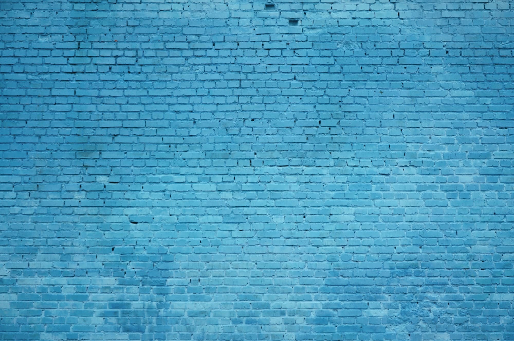 The texture of the brick wall of many rows of bricks painted in blue color